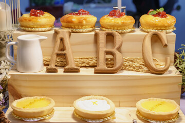 Assorted fruit tarts displayed on wooden steps with A B C wooden letters.