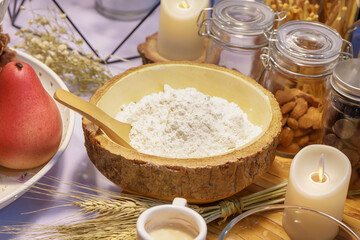 Wooden bowl filled with white all-purpose flour for baking with ingredients background.