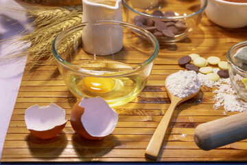 Baking ingredients including egg flour and chocolate chips arranged on a bamboo mat with tools.