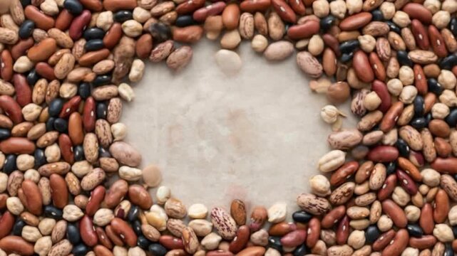 A vibrant assortment of diverse dried beans and legumes, including kidney beans, pinto beans, black beans, and chickpeas, gracefully swirls or falls into a dynamic, circular composition. The rich, ear