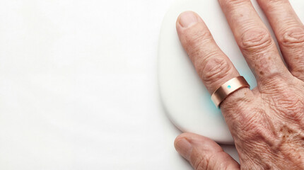Senior man finger wearing rose gold smart health tracking ring on white background.