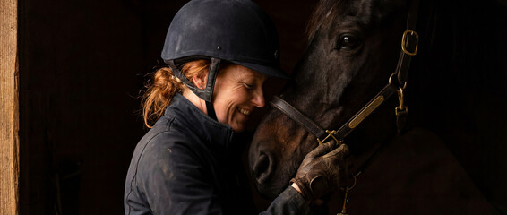 Woman with horse in barn during afternoon