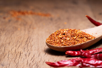Close-up of Asian seasoning chili powder in wooden spoon. Spicy condiment, cooking spice. Top view.