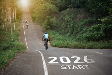 Naklejka premium New Year 2026. Cyclist Riding Up a Scenic Mountain Road with a 2026 Start Sign Symbolizing New Beginnings and Adventure in Nature