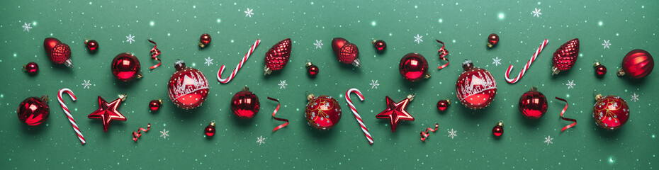 Christmas red decorations and candy on green background with glitter, lights. Merry Christmas and Happy New Year greeting card. Xmas and winter holidays. Christmas banner, top view