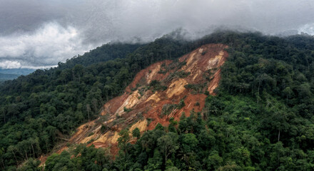 Massive tropical forest landslide shows exposed brown earth on a green mountain slope, highlighting natural disaster impact