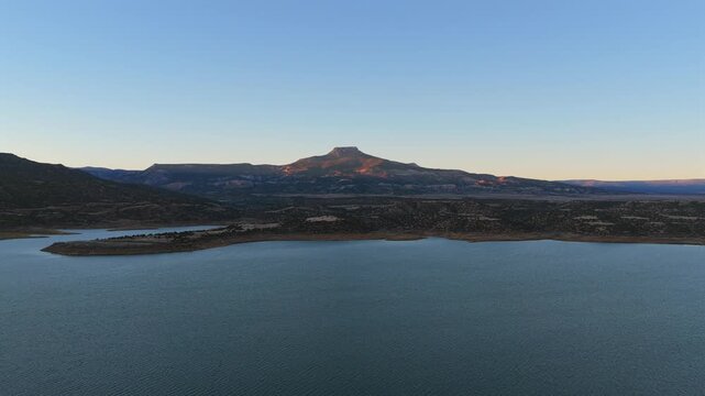 Wide aerial shot revealing the famous Cerro Pedernal mesa and the water of Abiquiu Lake. This classic New Mexico landscape was a primary subject for the iconic artist Georgia Okeeffe.