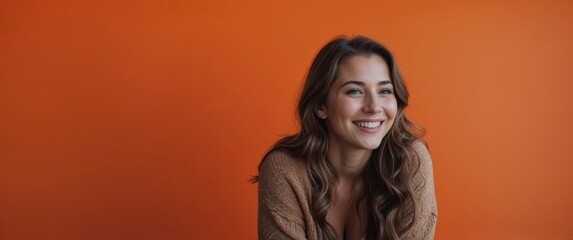 Young woman smiling in front of vibrant orange background
