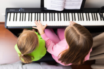 Young girls playing digital piano together indoors