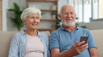 Older couple sitting on couch using smartphone