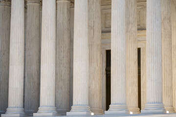 Naklejka premium Classical architecture defining monumental columns. Historic government architecture with marble pillars. White stone columns shaping civic architecture. Court house exterior with classical design.