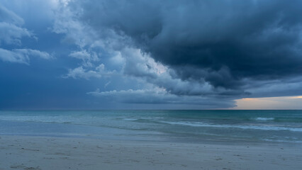Seascape before the rain. The waves of the turquoise ocean are foaming on the sandy beach. Dark clouds are swirling in the sky. Cuba. Varadero.