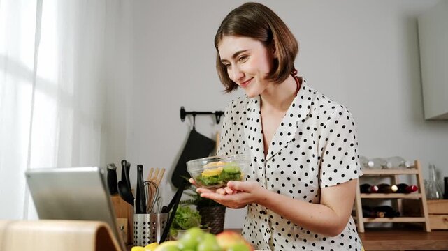 Caucasian mother put vegetable in bowl making a salad for breakfast while happy mom preparing fresh ingredients for salad at modern kitchen. House keeper cooking healthy meal. Care concept. Pedagogy.