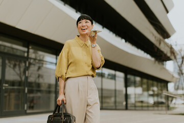 Woman enjoying her phone call while walking outside a modern building