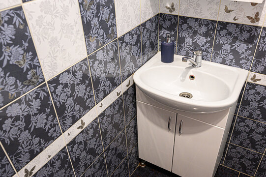 Elegant bathroom vanity with floral-patterned tiles in dark and light shades, providing a modern and stylish design with a vessel sink and plumbing fixtures - Powered by Adobe