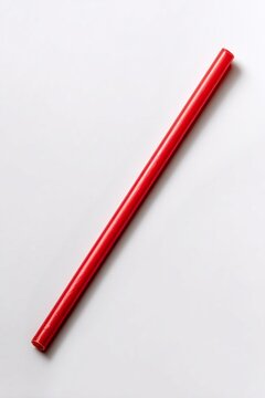 A striking red straw lies horizontally across a smooth white background, capturing attention with its bright hue
