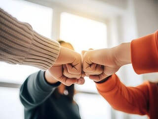 Close up of two people bumping fists in agreement celebrating success or showing support in a bright modern office setting