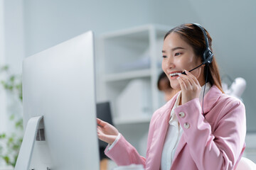 Portrait of smiling Businesswoman or Asian female operator speaking with client via headset,computer and talking in call center for contact us,help and online advice,engaging in communication concept
