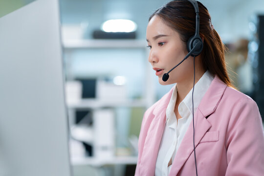 Portrait of smiling Businesswoman or Asian female operator speaking with client via headset,computer and talking in call center for contact us,help and online advice,engaging in communication concept