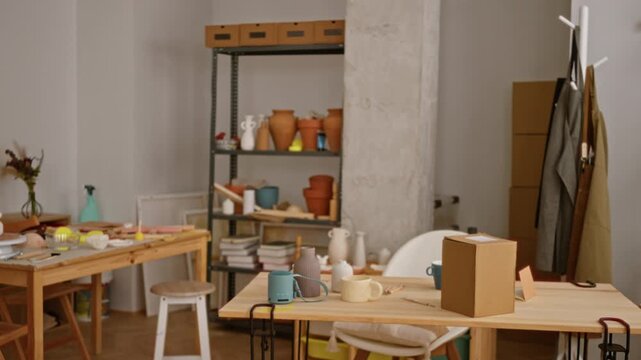 Ceramics studio interior with a shallow defocused soft background showing shelves, pottery and work tables; background backplate copyspace calm.