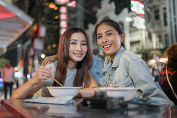 Portrait of Asian women traveler eating street food outdoors in the city. 