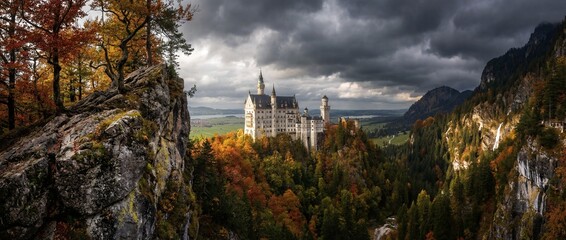 Castle sits on a hill surrounded by trees and mountains during autumn