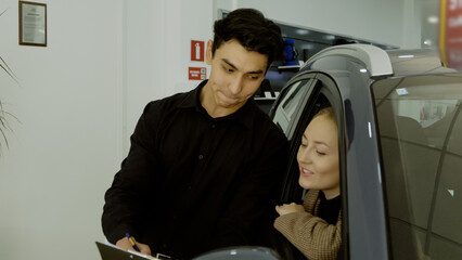 Sales manager and couple discussing car options in the showroom