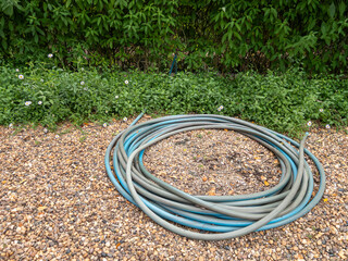 Garden Hose on Gravel Path in Outdoor Restaurant Garden.