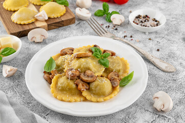 Tradition homemade Italian ravioli pasta with ricotta, mushrooms and parmesan cheese in a white plate on a concrete background. Top view.