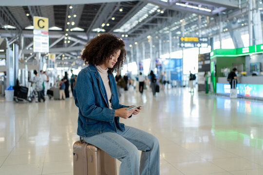 Latina traveler holding passport and boarding pass in airport terminal. 