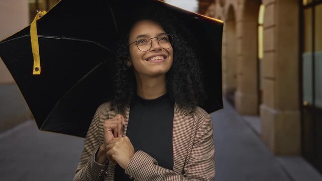 Woman smiling under an umbrella on a charming old town street exuding a sense of joy and warmth on a peaceful day with vintage architecture surrounding her lively outdoor experience.