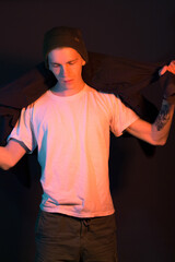 A teenager puts on a shirt against a black background