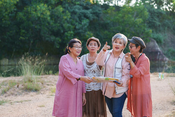 Senior Asian women discussing direction outdoor using map cheerful casual clothing vacation travel adventure exploring freedom leisure happiness refreshing friendship lifestyle relaxation journey