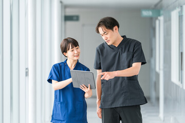 Male and female doctors, nurses, medical professionals, occupational therapists, and physical therapists talking in a hospital corridor