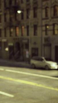 A bustling street intersection features green traffic lights with a yellow taxi waiting nearby. Buildings line the street under bright daylight, showcasing urban life.