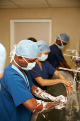 Surgeon team, man or washing hands in hospital with soap for medical procedure, disinfection or...