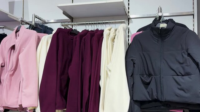 winter jackets and fleece sweaters displayed on clothing rack in retail store
