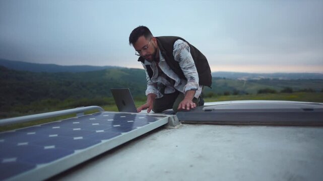 Professional technician using a laptop to check the functionality of solar panels installed on the roof of a recreational vehicle, promoting green energy for a sustainable travel lifestyle