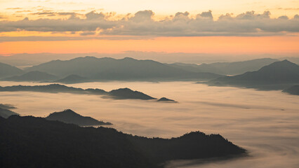 Obraz premium Serene Sunrise Over Misty Mountain Range with Vibrant Colors and Soft Clouds in the Sky, Capturing Nature's Beauty and Tranquility at Dawn