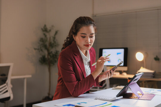 Woman working late reviewing reports using devices - Powered by Adobe