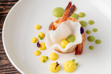Elegant shrimp dish served with colorful sauces and edible flowers