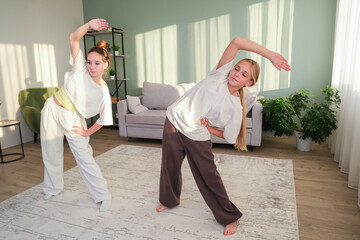 Teenagers practice fitness at home. Girls do sports exercises