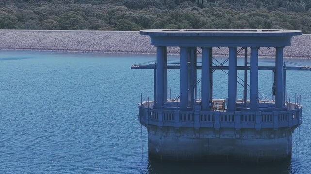 Aerial footage of Silvan Reservoir shows a tranquil water scene with a prominent architectural structure. Captured in daylight, the view highlights the serene aquatic surroundings. (199 characters)