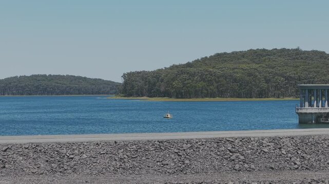 A stunning aerial view of Silvan Reservoir, showcasing deep blue waters encircled by lush green forests under a clear sky. Ideal for nature, travel, or geographical stock footage.
