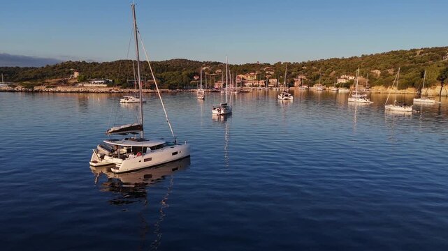 Kastos Island,aerial view ascending from the sea and moving forward towards the harbor on a sunny day.Birds eye view of the island,a motorboat and catamaran is just leaving the town quay.