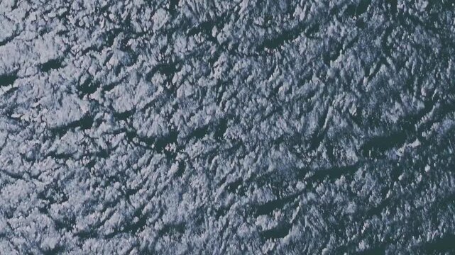 Experience the breathtaking aerial drone footage capturing the shimmering waves on Silvan Reservoir. The expansive, empty water body reflects the radiant sunlight.