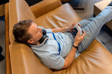 A young man is playing a game console, holding a gamepad in his hands © KseniaJoyg