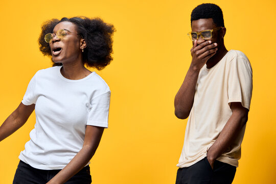 Joyful young African American couple laughing together against a bright yellow background wearing stylish glasses, conveying happiness and connection - Powered by Adobe