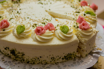 Celebration cake with pink rose icing, crushed nuts,  served on lace doily