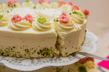 Celebration cake with pink rose icing, crushed nuts,  served on lace doily